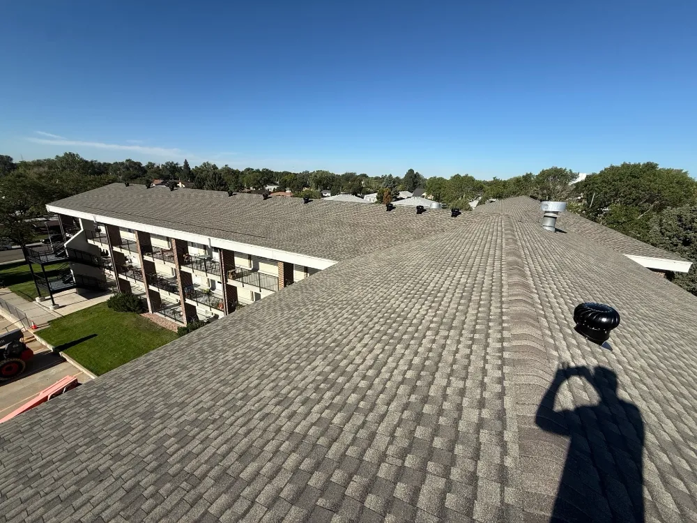 Asphalt shingle roof overlooking a multi-story apartment building with balconies in Englewood, CO.