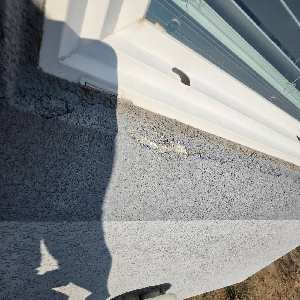 Corner of a stucco wall in Littleton, CO where a crack has been filled with sealant, next to a metal corner trim piece.